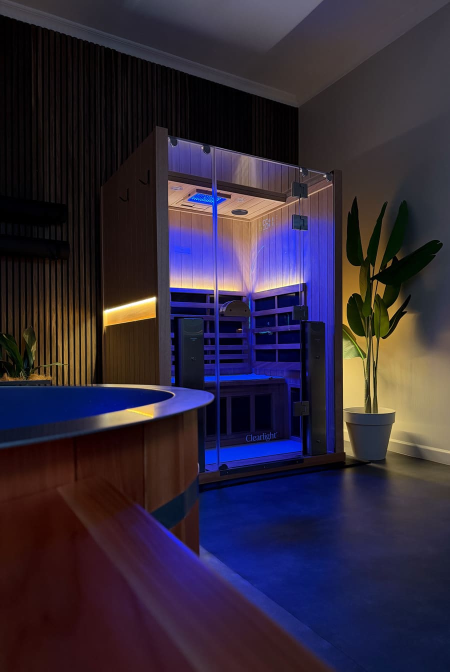 Warm infrared sauna beside the cold plunge, bathed in blue light